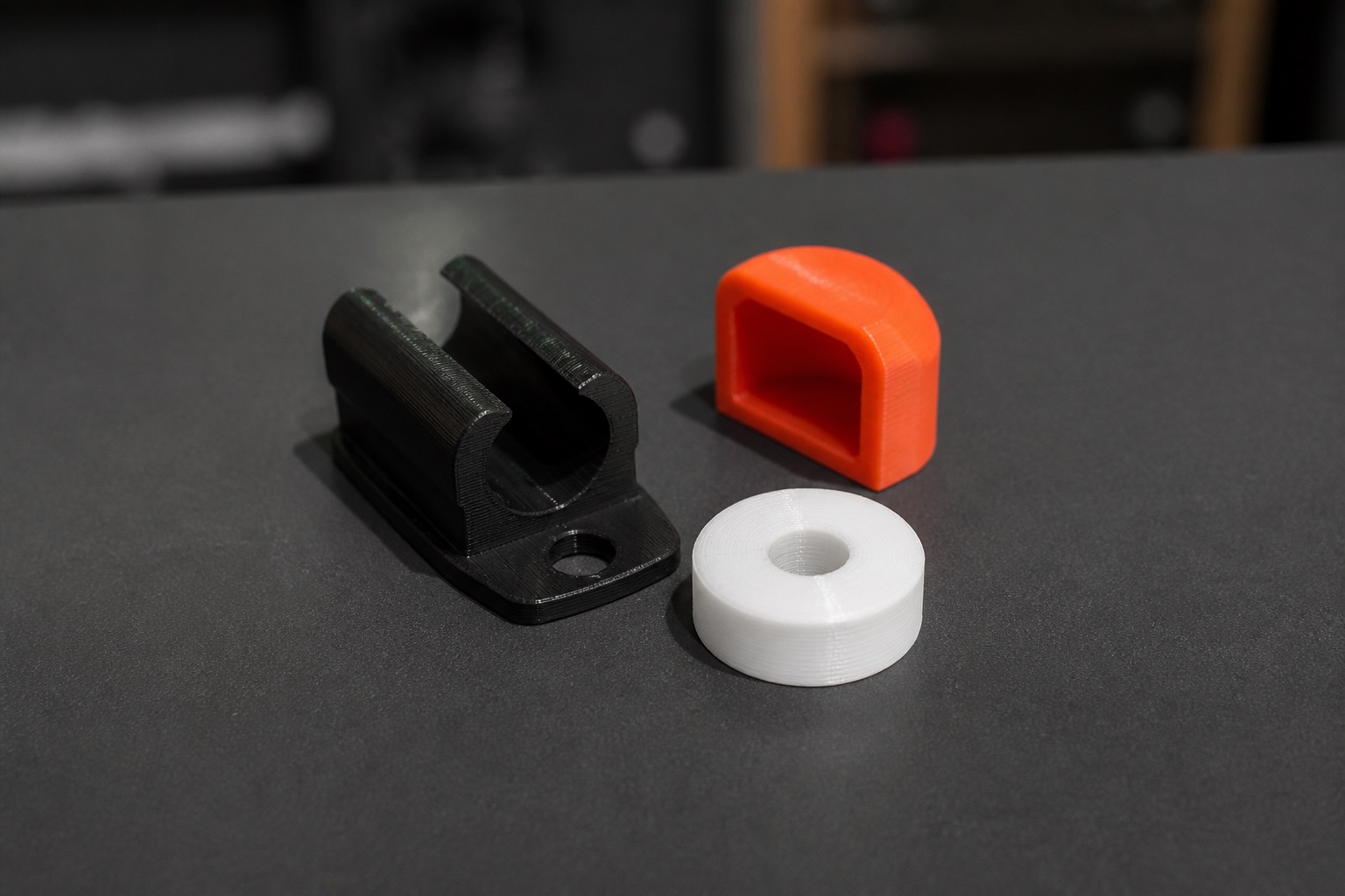 Three finished black orange and white 3D-printed functional parts